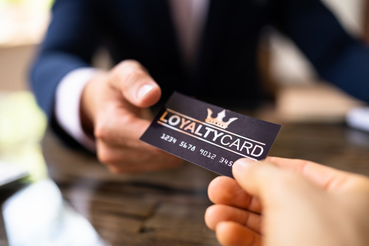 Customer passing a loyalty card to cashier. 