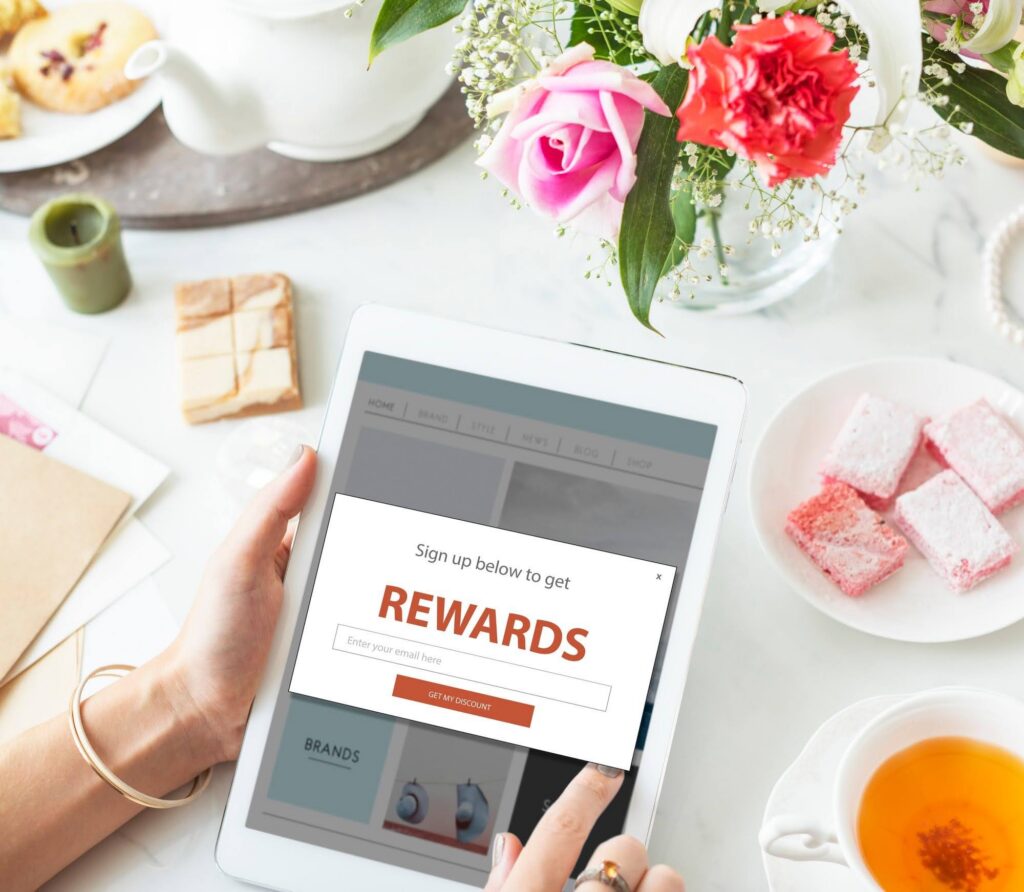 A person holding a tablet with a rewards menu on the display. Source - Freepik